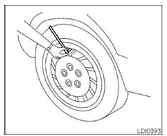 Using a mechanical pressure gauge to check tire inflation on a Nissan Versa wheel
